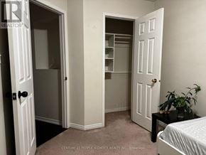 Mississauga (Meadowvale Village) townhouse for rent - A bedroom with a bed, a plant, and two doors.