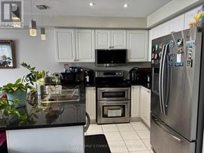 Mississauga (Meadowvale Village) townhouse for rent - A kitchen with a black counter top and stainless steel appliances.