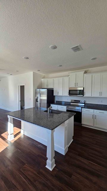 Tampa apartment for rent - A kitchen with white cabinets and a black countertop.