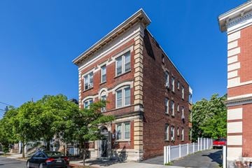 Montclair apartment for rent - A tall red brick building with a white fence in front.