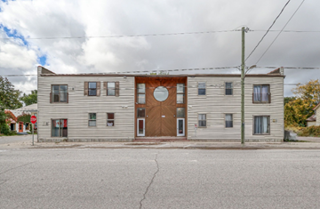 Dashwood apartment for rent - A grey building with a brown door and windows.