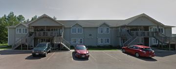 Moncton apartment for rent - A large building with a parking lot in front of it.