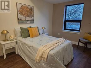 Arran-Elderslie multi-family for rent - A bedroom with a bed, nightstand, and window.