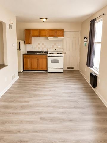 Philadelphia apartment for rent - A kitchen with wooden cabinets and a white stove top oven.