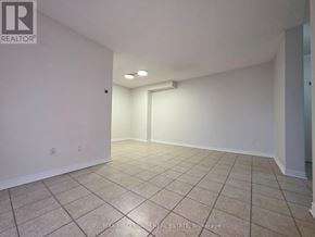 Toronto (Newtonbrook West) condo for rent - A spacious room with beige tiled flooring and white walls, featuring a large window and a doorway leading to another room.