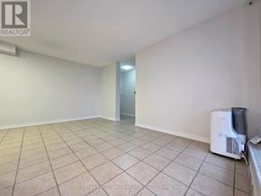 Toronto (Newtonbrook West) condo for rent - A spacious room with tiled flooring and white walls, with a doorway leading to another room.