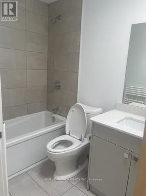 Toronto (Moss Park) condo for rent - A white toilet in a bathroom with a white tub and sink.