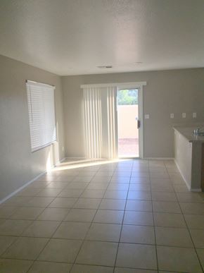 Las Vegas house for rent - an empty living room with a tiled floor and a door to a patio