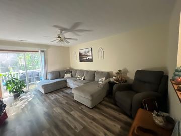 Clarksville apartment for rent - A living room with a grey couch and a ceiling fan.