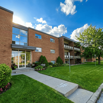 London apartment for rent - A modern brick building with a glass entrance and a well-maintained lawn in front.