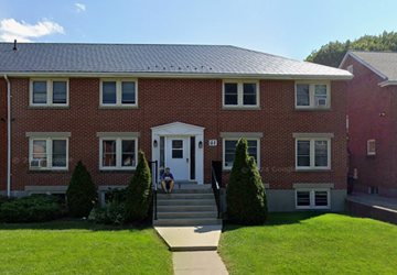 Oshawa apartment for rent - A red brick house with a white door and windows.