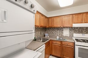 Parkville townhouse for rent - Kitchen with maple cabinets, white appliances, tile backsplash. and in-unit stacked laundry
