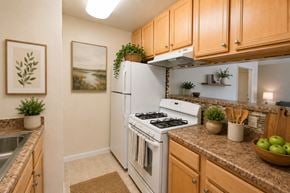 Fort Washington apartment for rent - A kitchen with a white stove top oven and wooden cabinets.
