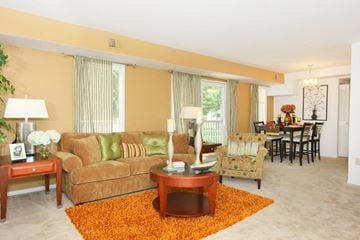Laurel apartment for rent - A living room with a brown couch, a coffee table, and a dining table with chairs.