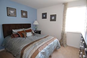 Parkville apartment for rent - A bedroom with a large bed and a window with curtains.