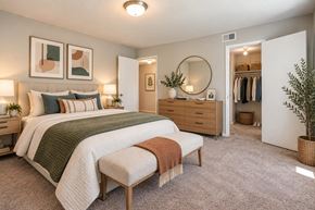 Laurel apartment for rent - A bedroom with a large bed, a bench, and a mirror.