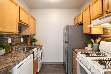 Laurel apartment for rent - A kitchen with a black refrigerator, white stove, and wooden cabinets.