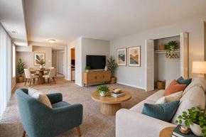 Laurel apartment for rent - A living room with a blue armchair, a grey sofa, a wooden coffee table, and a television.