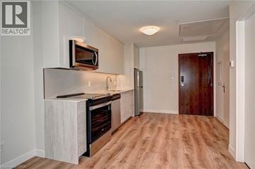 Kitchener condo for rent - A kitchen with a white counter top and a microwave on it.