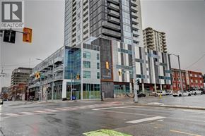 Kitchener condo for rent - A tall building with a glass facade is in the center of a city street.