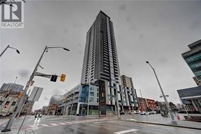 Kitchener condo for rent - A tall building stands in the middle of a city intersection.