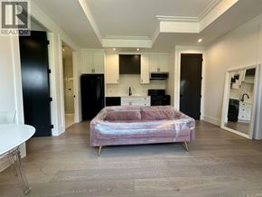 Vancouver house for rent - A bedroom with a bed, a table, and a fridge.