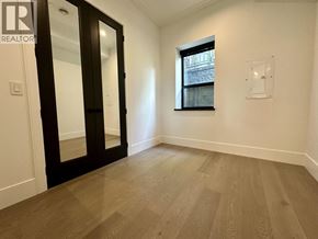 Vancouver house for rent - A room with a wooden floor and a window showing a building outside.