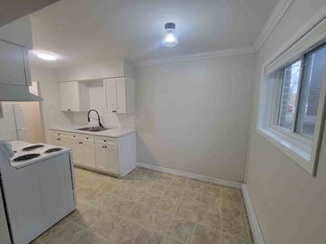 Pictou apartment for rent - A kitchen with white cabinets and a tiled floor.