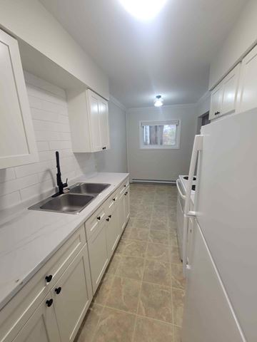 Pictou apartment for rent - A kitchen with white cabinets and a sink.