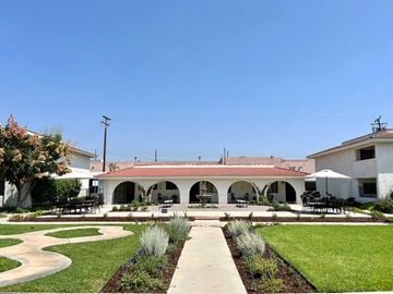 Brea apartment for rent - A white building with a red roof and a green lawn in front.
