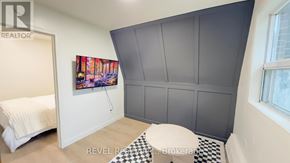 Toronto (Roncesvalles) condo for rent - A bedroom with a bed, a painting, and a checkered floor.