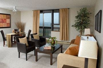 Ottawa apartment for rent - A living room with a brown couch, a coffee table, and a dining table with chairs.