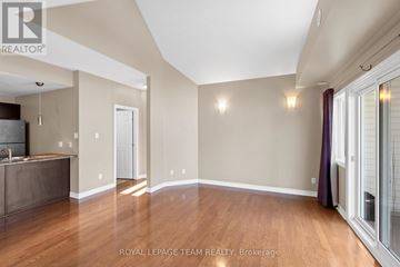 Ottawa condo for rent - A spacious room with wooden floors and a kitchen area with a sink and stove.