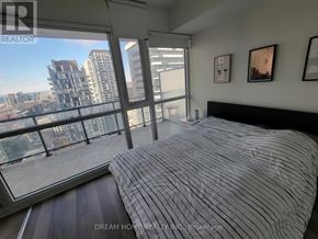 Toronto (Waterfront Communities) condo for rent - A bedroom with a large bed and a view of the city.