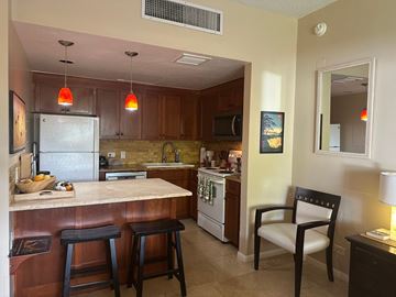 Kailua-Kona apartment for rent - A kitchen with a refrigerator, stove, and bar stools.