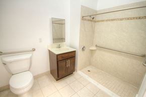 Camden apartment for rent - Bathroom with white tiles, wooden cabinet and handicap shower