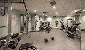 Toronto apartment for rent - A gym with a variety of equipment and a person standing in the background.