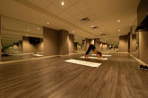 Toronto apartment for rent - A woman is practicing yoga in a spacious room with wooden floors.