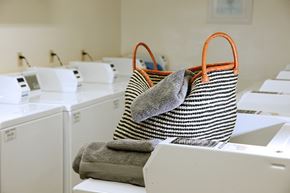 Toronto apartment for rent - A striped bag with orange handles is filled with towels and is placed on top of a washing machine.