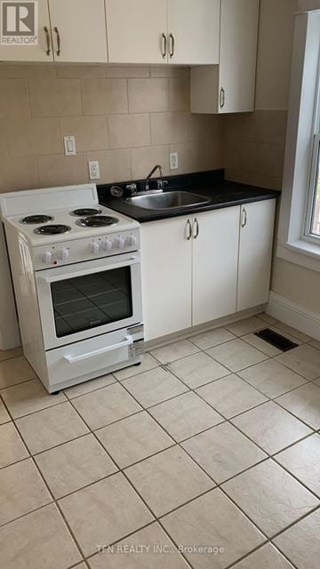Welland (Broadway) multi-family for rent - A white stove in a kitchen with beige tiles.