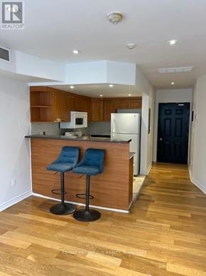 Toronto (Greenwood-Coxwell) house for rent - A kitchen with a bar stool and a fridge.