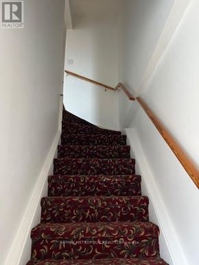 Toronto (Greenwood-Coxwell) house for rent - A staircase with a red carpet and wooden handrails.