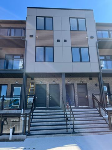 Fergus apartment for rent - A building with a brown and beige exterior has a black door and a staircase leading to the entrance.
