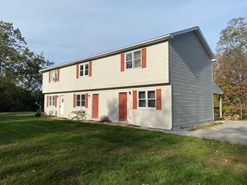 Lewistown apartment for rent - A two-story house with a grey exterior and red trim.