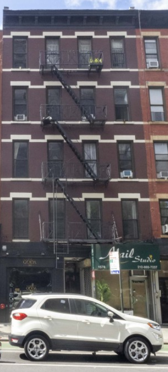 New York apartment for rent - A white car is parked on the street in front of a red brick building.
