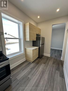 For rent in North Grenville - A kitchen with a stove top oven and a refrigerator with a cabinet above it.
