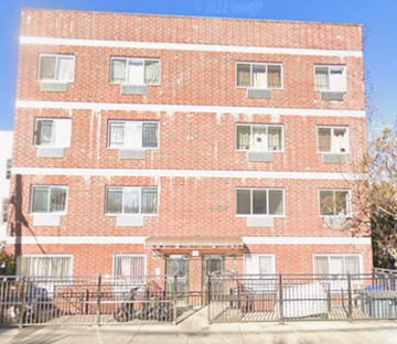 Bronx apartment for rent - A red brick building with a black fence in front.