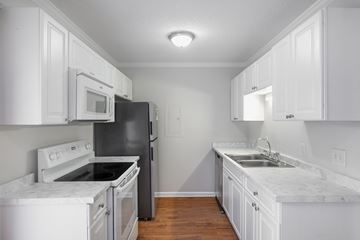 Charleston apartment for rent - A kitchen with white cabinets and a black refrigerator.