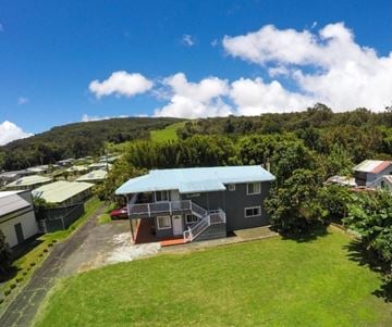 Kailua-Kona apartment for rent - A house with a blue roof is surrounded by greenery and other houses.