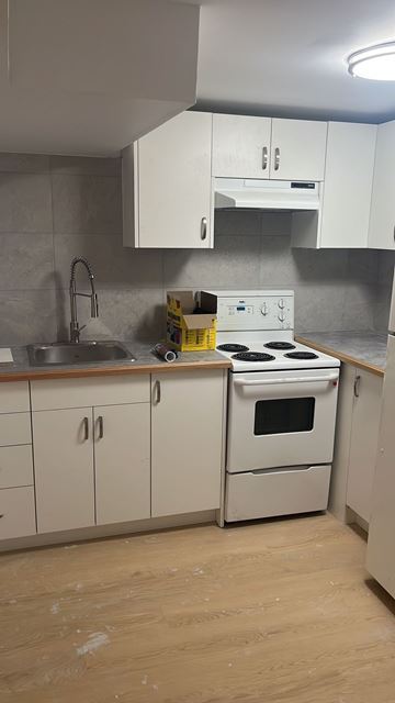 North Bay apartment for rent - A kitchen with white cabinets and a stove top oven.